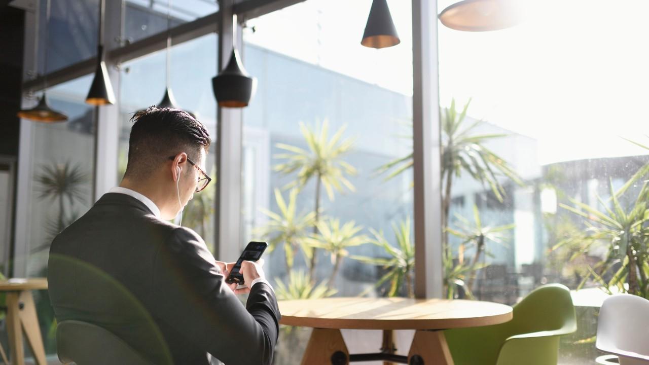 Homem de terno trabalhando no telefone, ouvindo música com fones de ouvido